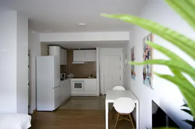 a white kitchen with a table and a refrigerator at Apartamento San Juan in El Puerto de Santa María