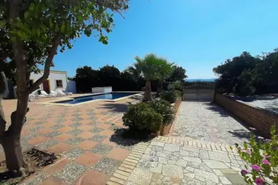a stone walkway leading to a house with a pool at Finca La Parrilla Maison Piscine nature chevaux in Arcos de la Frontera