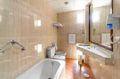 a bathroom with a tub and a toilet and a sink at Hotel Guadalquivir in Sanlúcar de Barrameda