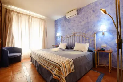a bedroom with a bed with a blue wall at Hotel Guadalquivir in Sanlúcar de Barrameda