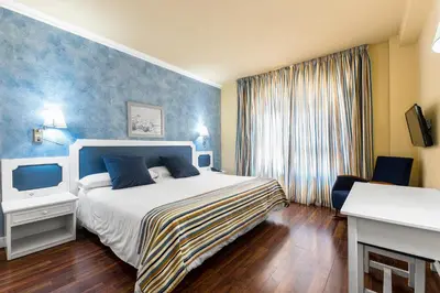 a hotel room with a bed and a television at Hotel Guadalquivir in Sanlúcar de Barrameda