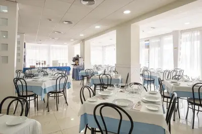 a dining room with tables and chairs with white and blue tablecloths at Hotel Guadalquivir in Sanlúcar de Barrameda