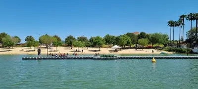 a pier in the water with a beach and people at Studio andalou , campagne , chevaux , piscine commune in Arcos de la Frontera