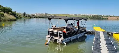 a small boat parked at a dock in the water at Studio andalou , campagne , chevaux , piscine commune in Arcos de la Frontera