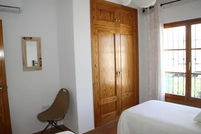 a bedroom with a bed and a chair and a window at Penthouse Sleeps 4 with Private Garden in Chipiona
