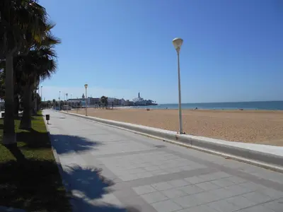 a sidewalk next to a beach with a light pole at Penthouse Sleeps 4 with Private Garden in Chipiona