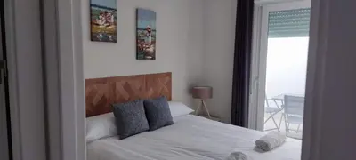 a bedroom with a white bed with blue pillows at Guesting Hospital in Cádiz