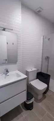 a white bathroom with a toilet and a sink at Guesting Hospital in Cádiz