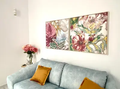 a living room with a blue couch and two paintings on the wall at innCádizCasa Señorial Rivadavia in Cádiz
