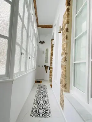 a hallway with white walls and windows and a tile floor at innCádizCasa Señorial Rivadavia in Cádiz