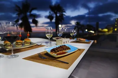 a table with two plates of food and glasses of wine at Hotel Agaró in Chipiona