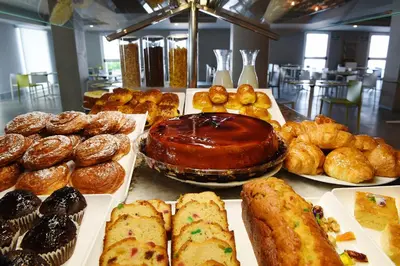 a table filled with different types of pastries and pies at Hotel Agaró in Chipiona