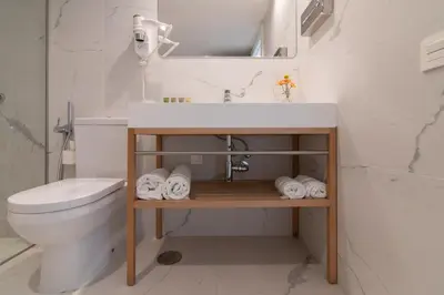 a white bathroom with a sink and a toilet at Hotel Agaró in Chipiona