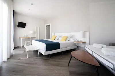 a bedroom with a large bed and a couch at Hotel Agaró in Chipiona