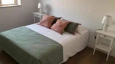 a bed with pink and green pillows on it at Apartamento Victoria in Cádiz