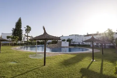 a swimming pool with umbrellas in a park at Duplex Near the Beach in Chiclana de la Frontera