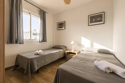 two beds in a room with a window and two towels at Beautiful Duplex in Chiclana de la Frontera
