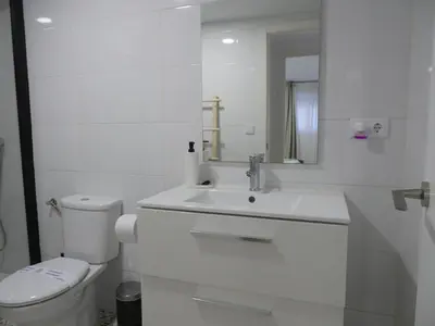 a white bathroom with a toilet and a sink at Aromas de Bodega in Jerez de la Frontera