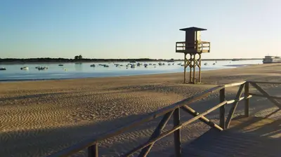 a life guard stand on a beach with boats in the water at Piso de dos dormitorios en el centro de Sanlúcar de Barrameda in Sanlúcar de Barrameda