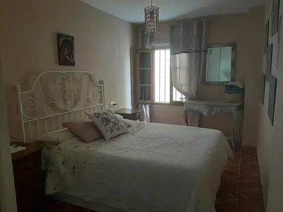 a bedroom with a white bed and a window at Piso de dos dormitorios en el centro de Sanlúcar de Barrameda in Sanlúcar de Barrameda