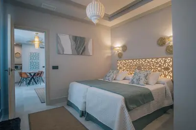 a bedroom with a bed and a hallway with a table at Apartamentos Turísticos La Baílla in Rota