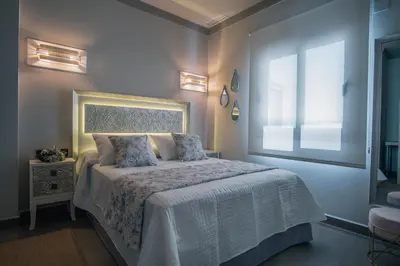 a bedroom with a white bed with a window at Apartamentos Turísticos La Baílla in Rota