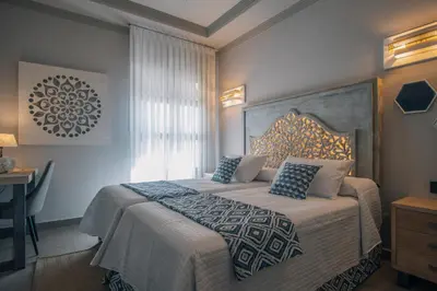 a bedroom with a large bed with blue pillows at Apartamentos Turísticos La Baílla in Rota