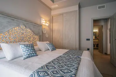 a bedroom with a large bed with blue and white pillows at Apartamentos Turísticos La Baílla in Rota