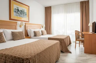 a hotel room with two beds and a desk at ALEGRIA Costa Ballena Aquafun in Costa Ballena