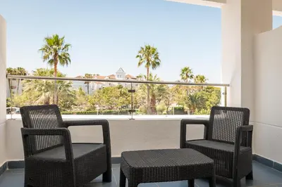 two chairs and a table on a balcony with palm trees at ALEGRIA Costa Ballena Aquafun in Costa Ballena
