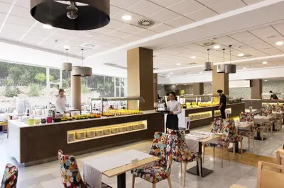 a restaurant with tables and chairs and people preparing food at ALEGRIA Costa Ballena Aquafun in Costa Ballena
