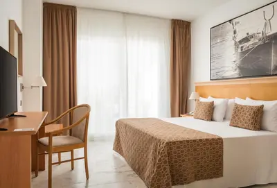 a hotel room with a bed and a desk and a television at ALEGRIA Costa Ballena Aquafun in Costa Ballena