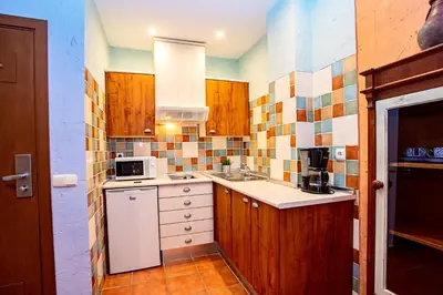 a small kitchen with a sink and a microwave at Apartahotel La Espadaña in Rota