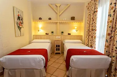 a room with two beds and a mirror at Apartahotel La Espadaña in Rota