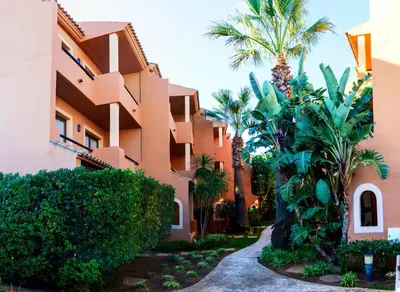 a building with palm trees in front of it at Apartahotel La Espadaña in Rota