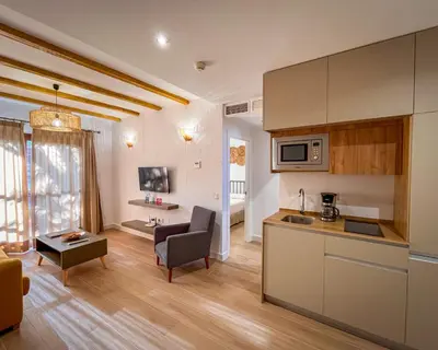 a kitchen and living room with a couch and a table at Apartahotel La Espadaña in Rota
