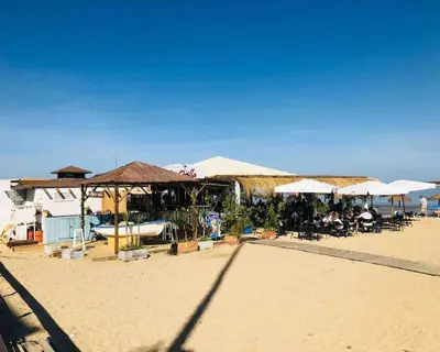 a beach with tables and umbrellas on the sand at Sanlúcar Playa de las Piletas in Sanlúcar de Barrameda