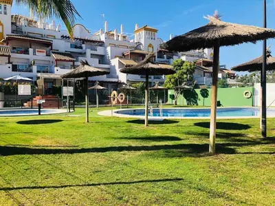 a park with umbrellas and a swimming pool at Sanlúcar Playa de las Piletas in Sanlúcar de Barrameda