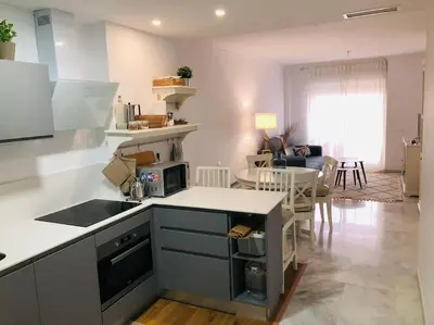 a kitchen with a counter and a living room at Sanlúcar Playa de las Piletas in Sanlúcar de Barrameda