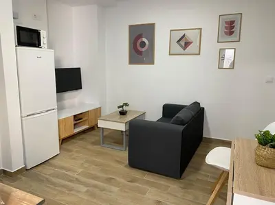 a living room with a black chair and a white refrigerator at Precioso apartamento con patio/terraza Zona centro in Jerez de la Frontera