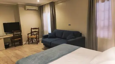 a room with a bed and a couch and a television at Hotel Doña Blanca in Jerez de la Frontera