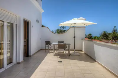 a patio with an umbrella and a table and chairs at Apartamentos Piedramar in Conil de la Frontera
