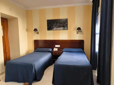 a hotel room with two beds and a desk at Hotel Nova Centro in Jerez de la Frontera