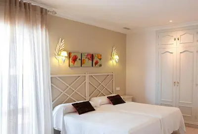 a bedroom with two beds with white sheets at Apartamentos Turísticos Los Patios in Rota