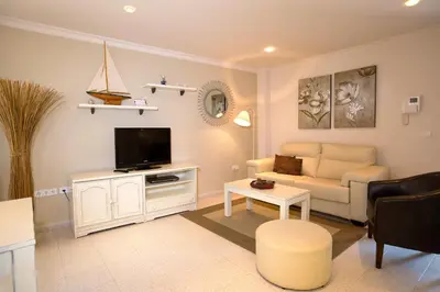a living room with a couch and a tv at Apartamentos Turísticos Los Patios in Rota