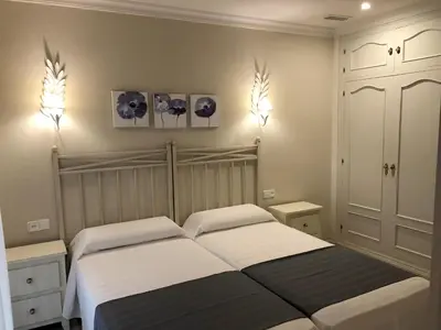 a bedroom with two beds and two lights on the wall at Apartamentos Turísticos Los Patios in Rota