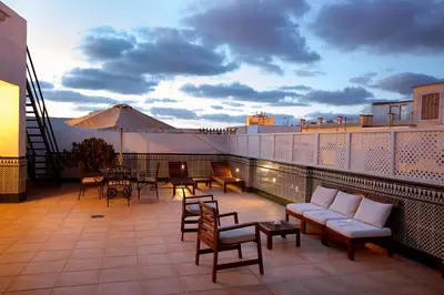 a balcony with a couch and tables and chairs at Apartamentos Turísticos Los Patios in Rota