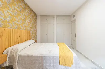 a bedroom with a bed with a yellow blanket at Allo Apartments Porvenir Centro 1 Habitación in Jerez de la Frontera