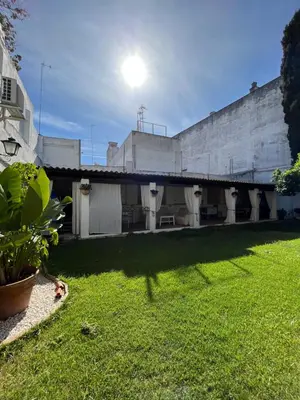 a building with a green yard with the sun behind it at Jardin Bizcocheros in Jerez de la Frontera