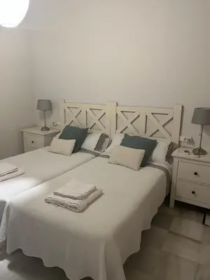 a bedroom with two beds with white sheets and two lamps at Jardin Bizcocheros in Jerez de la Frontera